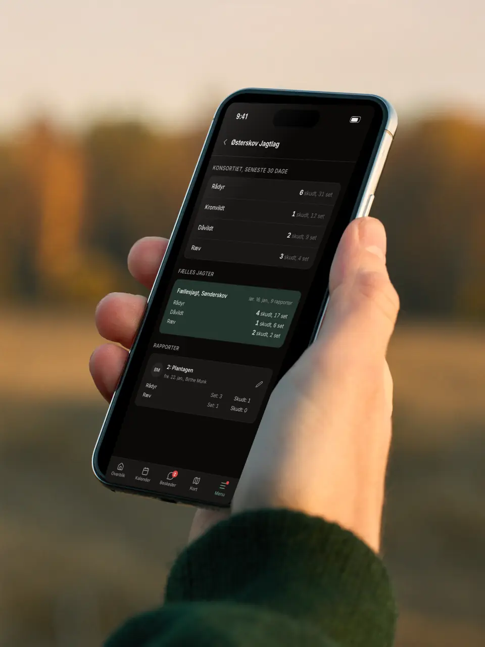 Jæger med telefon, der viser konsortiets jagtrapporter